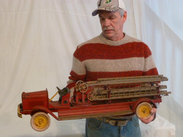 KINGSBURY AERIAL LADDER FIRE TRUCK: SHOWING A KINGSBURY AERIAL LADDER TOY FIRE TRUCK , PRESSED STEEL , OPEN FRONT CAB . MEASURES 34" LONG .PLEASE USE PHOTOS AS PART OF THE DESCRIPTION. THE ABSENCE OF A CONDITION REPORT DOES NOT GUARANTE