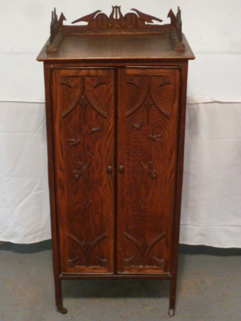 C1900 OAK MUSIC CABINET CARVED TOP: SHOWING A CIRCA 1900'S OAK MUSIC CABINET WITH AN INTRICATELY CARVED TOP . BIRDS , HARPS AND HORSES . MEASURES 19" BY 14" AND 43" TALL. AS FOUND ESTATE CONDITION.PLEASE USE PHOTOS AS PART OF THE DESCRI