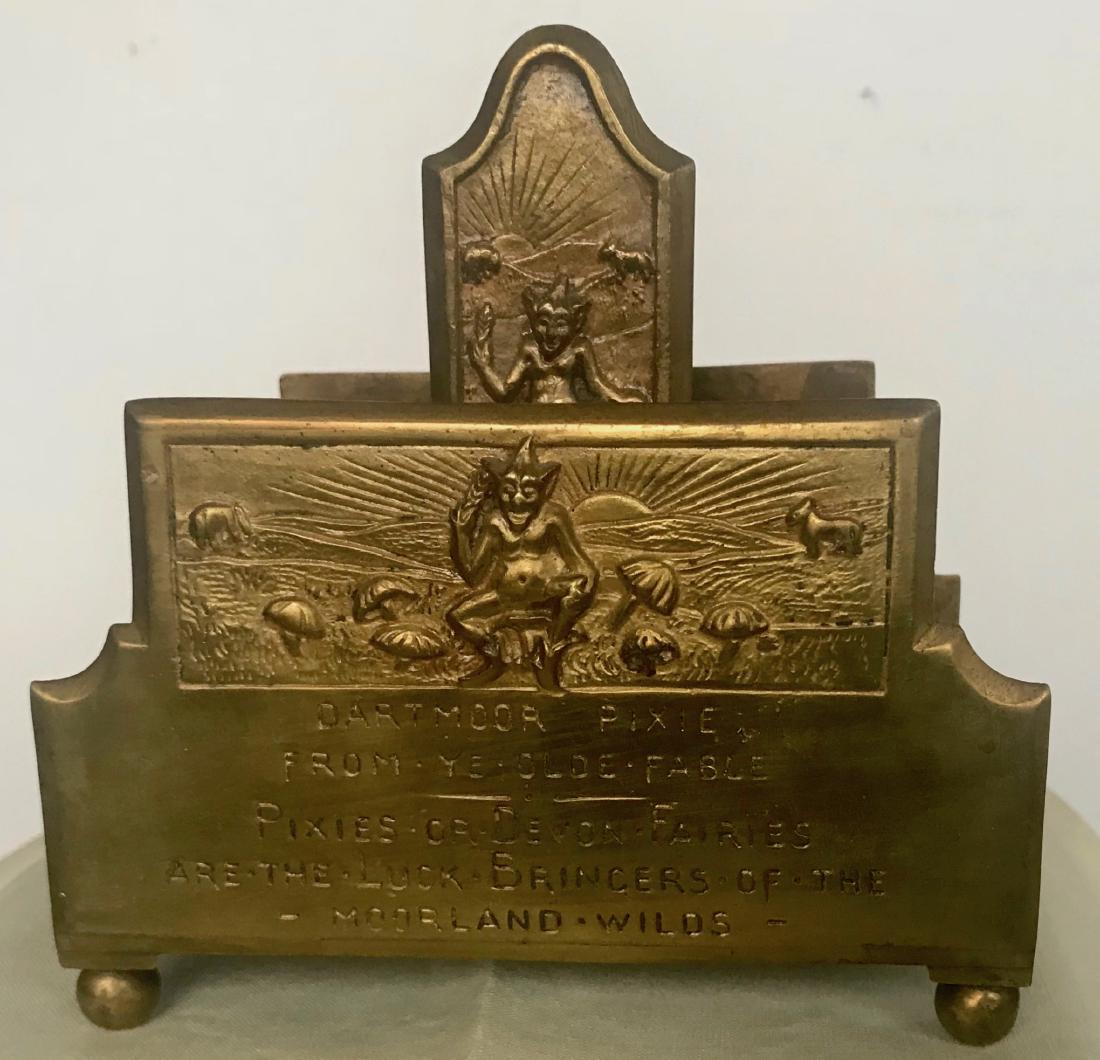 Dartmoor England Elf Pixie Letter Rack MOORLAND WILDS: Antique Bronze Dartmoor Elf Pixie Desk Letter Rack, England. Elf Pixies are the protectors of the English Moorlands. Image of Pixie with toadstools, elephant and dog in the distance. Dimensions: 5 in.