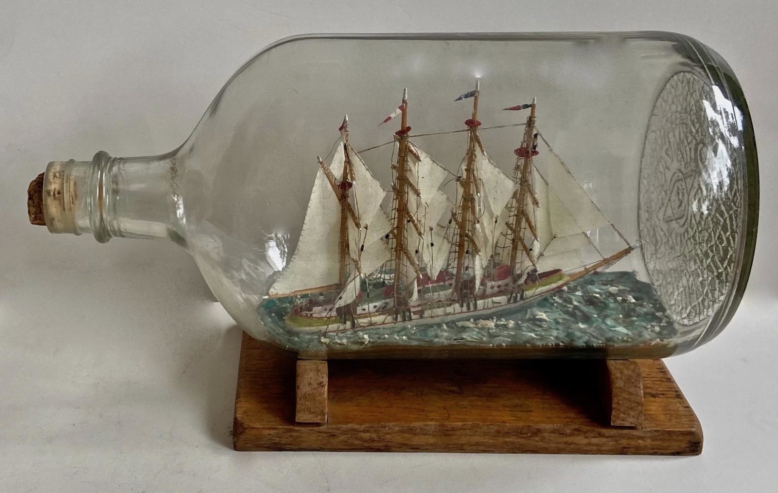 Antique Folk Art Ship In A Bottle On Custom Wood Mount, Halifax, Nova Scotia: Antique Vintage Folk Art Four-Masted Clipper Ship Diorama in an Early Large Bottle, displayed on a custom wood stand. Dimensions: 8 in. hgt. x 16 in. lg. x 7 1/2 in. dp. Height on stand: 9 1/2 in. Con