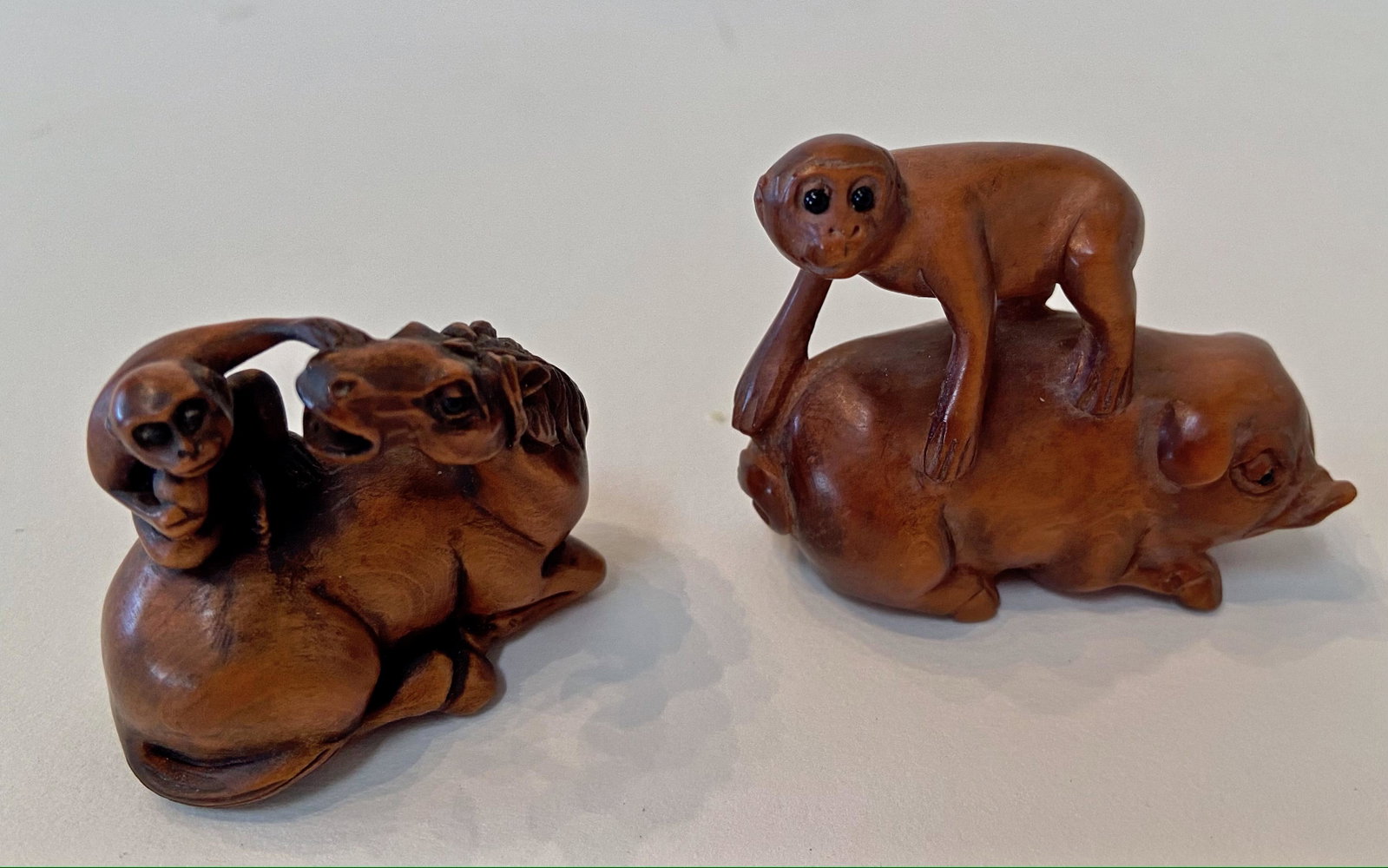 Japanese Carved Wood Netsuke, Artist Signed: Two Japanese Carved Wood Netsuke Animal Figures. Monkey atop Hog, signed by the artist. Dimension: height 1 5/8 in. Monkey atop Horse, signed by the artist. Dimension: height 1 1/2 in. Condition: both