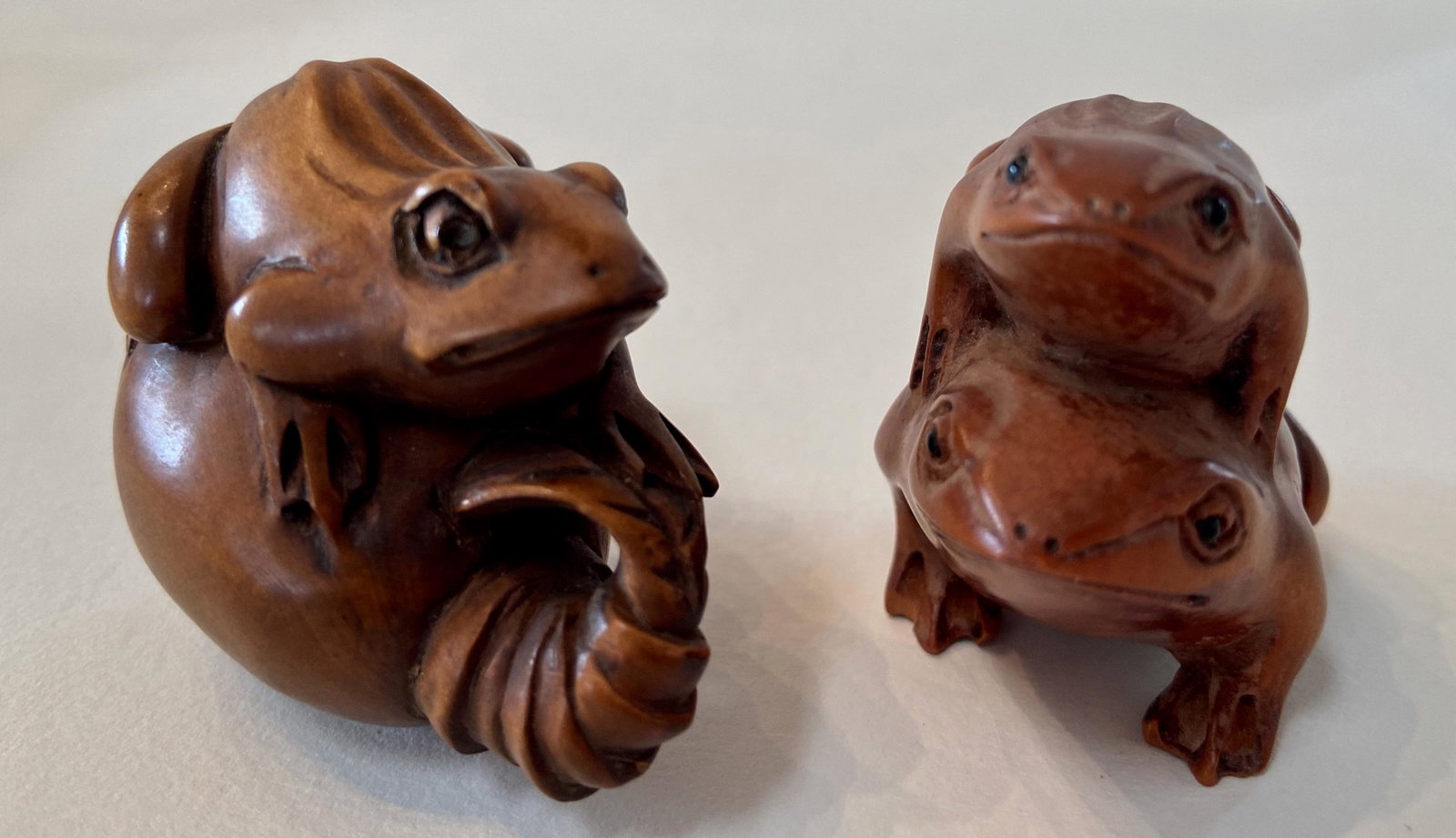 Japanese Carved Wood Netsuke, Form of Frogs: Two Carved Japanese Wood Netsuke. Frog seated on acorn, signed by the artist. Dimension: height: 1 5/8 in. Frog atop Frog. Dimension: height: 1 5/8 in. Condition: good original estate condition. Prove