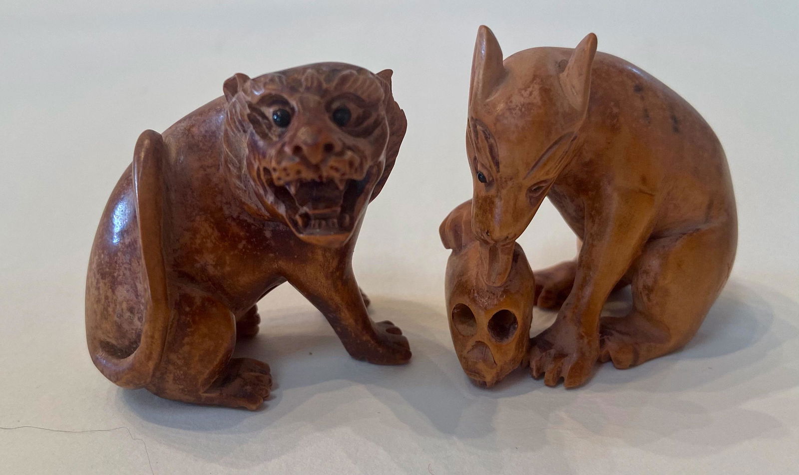 Two Japanese Carved Wood Netsuke, Form of Hyena w/ Skull & Crouching Tiger: Japanese Carved Wood Netsuke Animal Figures. Hyena with Human Skull. Dimension: height: 1 3/4 in. Crouching Tiger. Dimension: height: 1 1/2 in. Condition: good original estate condition. Provenance: B