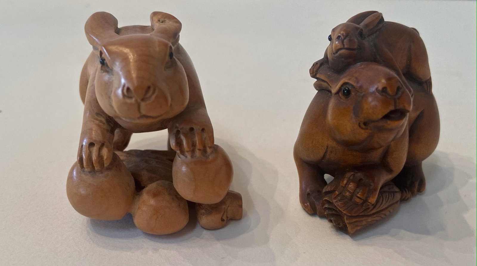 Japanese Carved Wood Netsuke, Rabbit w/ Nuts & Rabbits (2): Two Japanese Carved Wood Netsuke Animal Figures. Rabbit with stash of nuts, signed by the artist. Dimension: height: 1 3/4 in. Rabbit atop Rabbit. Dimension: height: 1 3/4 in. Condition: good original