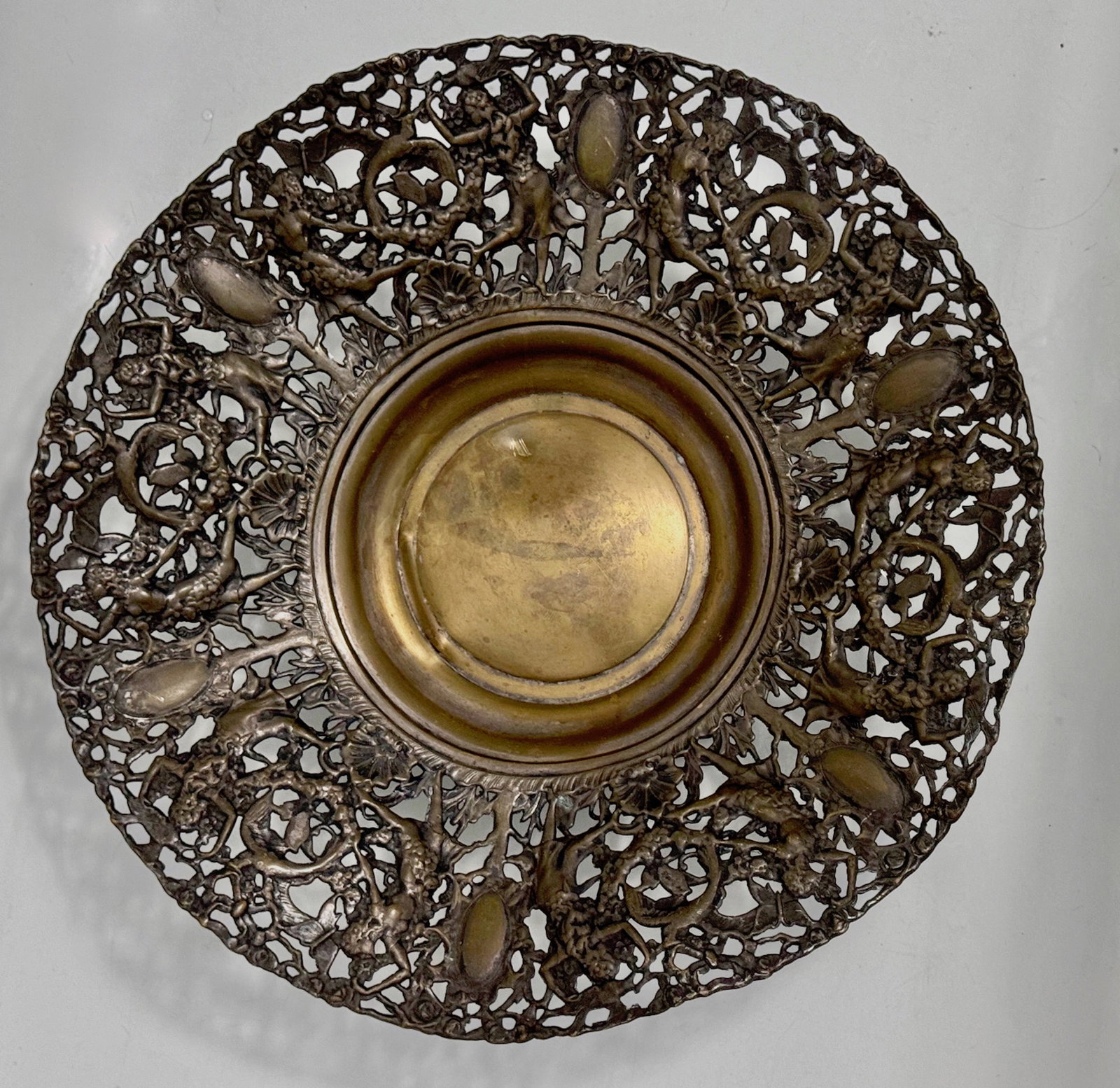 Vintage Reticulated Pierced Basket With Dancing Women & Butterflies: Bacchus Imagery. Vintage openwork centerpiece with pierced gilt brass and a trellis embellished with butterflies, dancing women and floral designs throughout. Dimension: diameter: 16 in. Good original