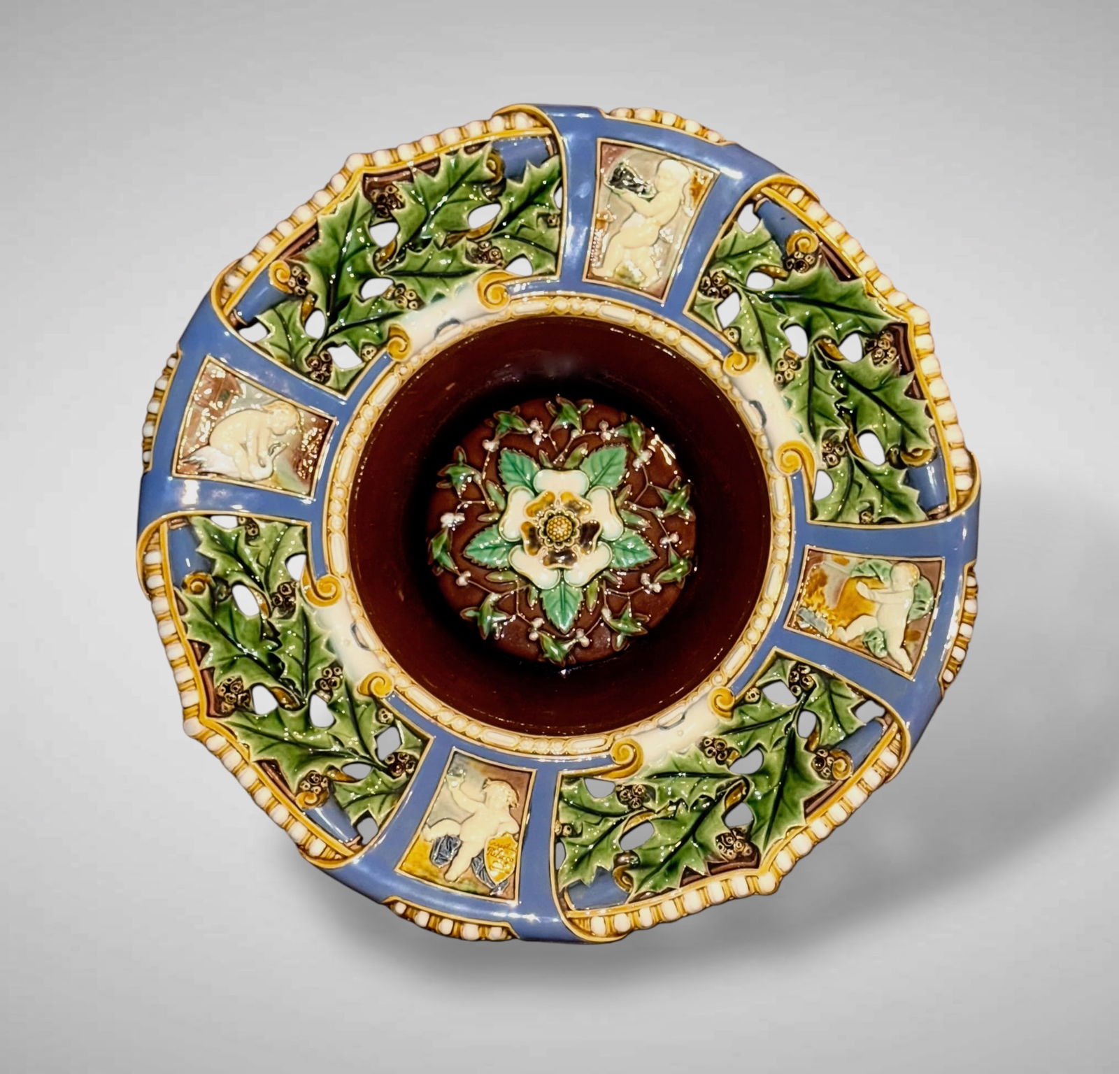 Minton Majolica Christmas Charger. c. 1859: 19th Century Minton Majolica Christmas Charger. Moulded with a tudor rose within mistletoe, below a cruiciform border with pierced sections of holly between panels of putti at festive persuits, below