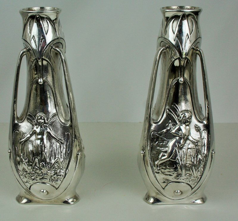 Antique Art Nouveau Pixie Vases (Pair): A pair of Art Nouveau Pixie Vases. White metal with a silver plated finish. Missing the glass liners. Signed J. Garnier. Circa 1890's. 15"H and 6" across.
