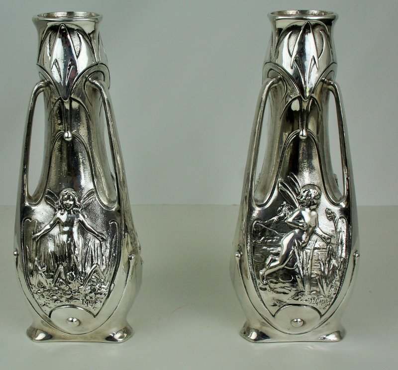 Antique Art Nouveau Pixie Vases (Pair): A pair of Art Nouveau Pixie Vases. White metal with a silver plated finish. Missing the glass liners. Signed J. Garnier. Circa 1890's. 15"H and 6" across.