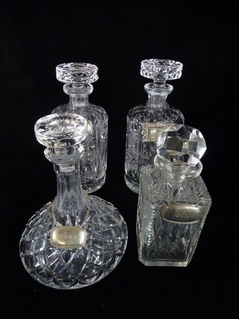 4 CRYSTAL DECANTERS W/ SILVER PLATE LIQUOR TAGS 10 1/2" HIGH TALLEST (CHIPS ON MOUTH OF ONE): 4 CRYSTAL DECANTERS W/ SILVER PLATE LIQUOR TAGS 10 1/2" HIGH TALLEST (CHIPS ON MOUTH OF ONE)