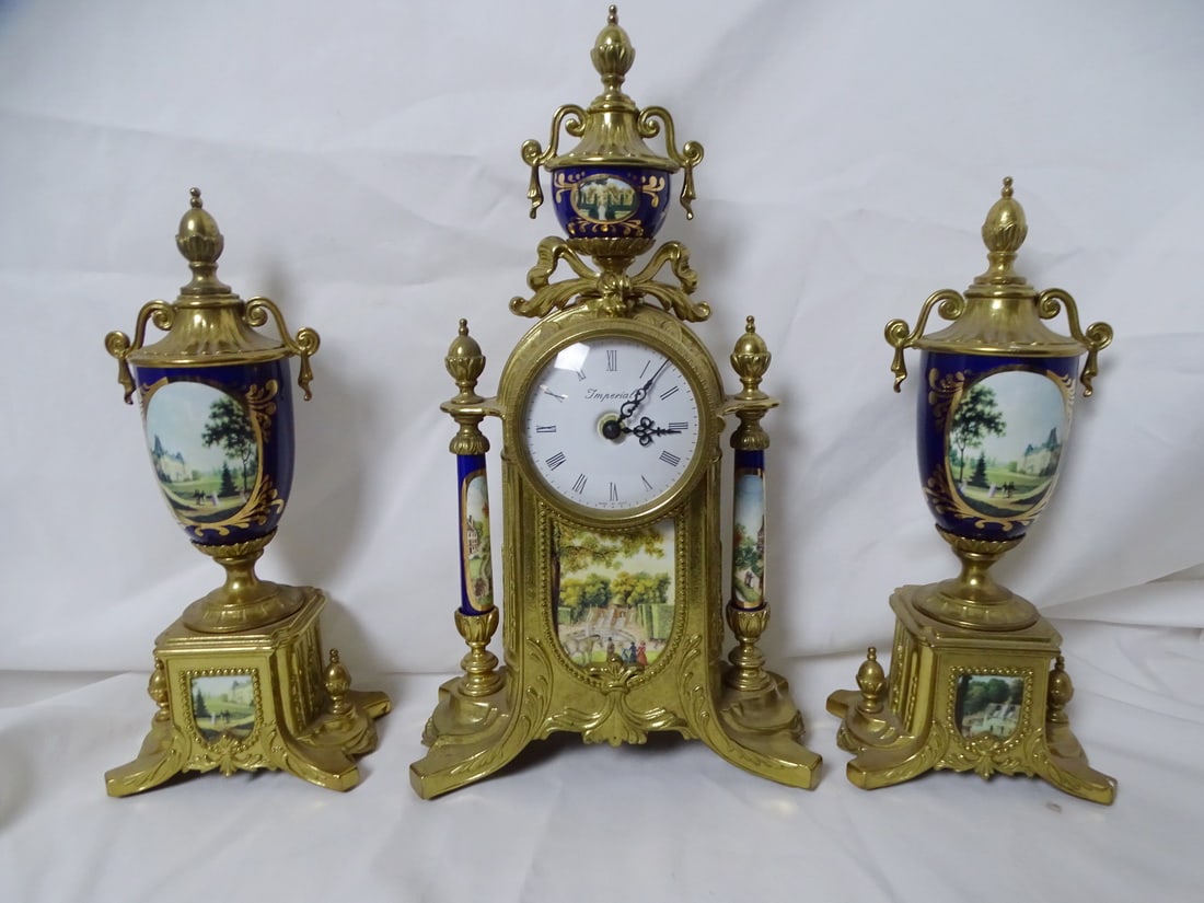 "IMPERIAL" ITALY BRASS AND PAINTED PORCELAIN CLOCK GARNITURE, BATTERY MOVEMENT, 16.75" TALLEST: An exquisite "Imperial" Italy brass and painted porcelain clock garniture, measuring 16.75 inches at its tallest point, offers a captivating blend of elegance and historical style. This stunning ensem