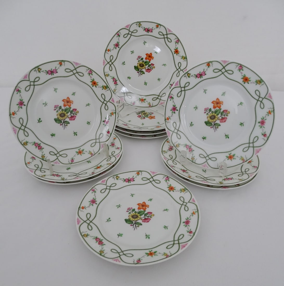 SET OF TEN REYNAUD LIMOGES GUIRLANDES CERALEN DESSERT PLATES: This set of ten Reynaud Limoges Guirlandes Ceralen dessert plates is a testament to the artistry and craftsmanship of French porcelain. The delicate floral motif, known as the Guirlandes pattern, is m