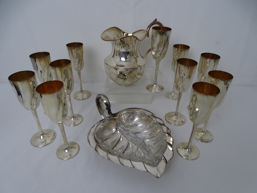 COLLECTION OF SILVER PLATED ITEMS: This collection of silver-plated servingware offers a blend of elegance and functionality. The set includes a stylish pitcher, a versatile serving dish, and a set of eleven champagne flutes. The pitch