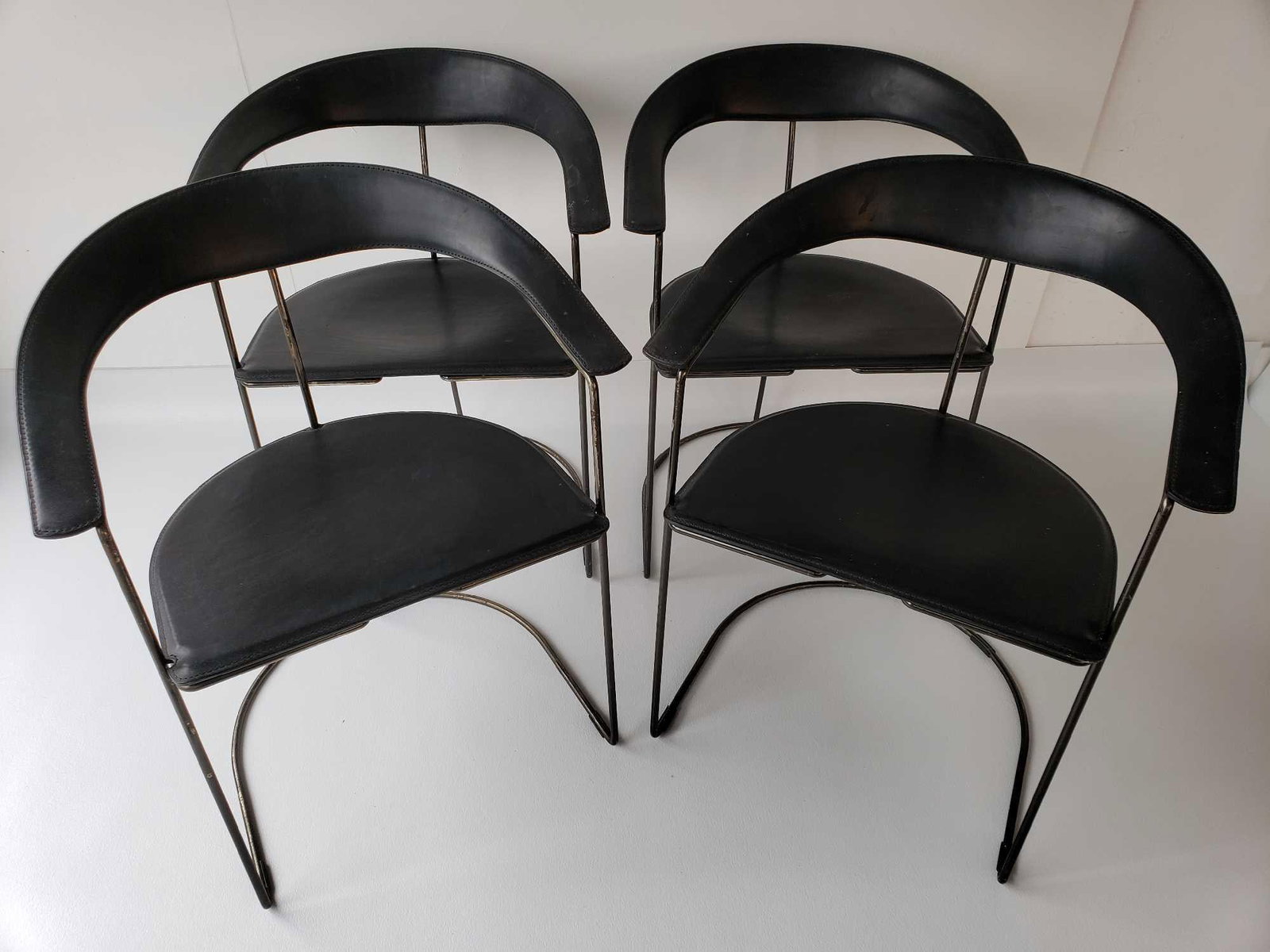 SET OF FOUR ARRBEN ITALIAN STEEL AND LEATHER CHAIRS: This set of four "Arrben" Italian steel and leather mid-century modern chairs embodies the sleek, minimalist aesthetic characteristic of Italian design from that era. These stylish chairs feature a ca