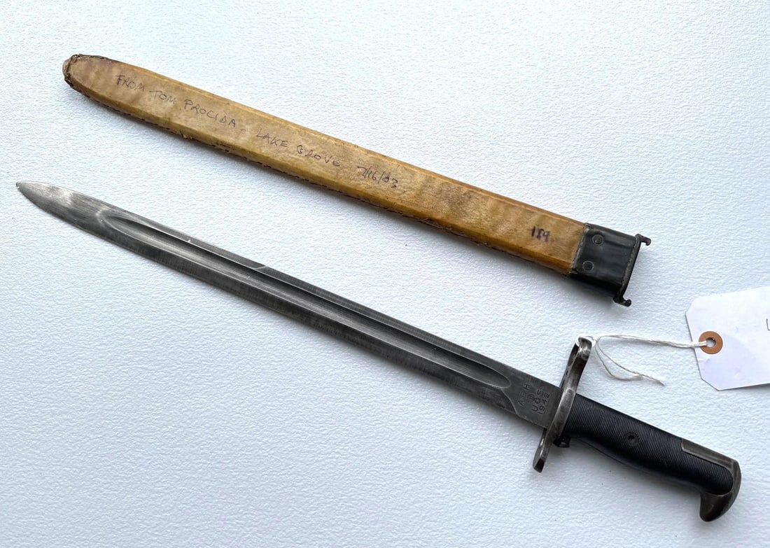 AHF. US FLAMING BOMB M1 GARAND LONG BAYONET: This is a U.S. M1905 bayonet, which is distinguished by its long blade and iconic "flaming bomb" ordnance marking. These bayonets were designed for the M1903 Springfield rifle and later adapte