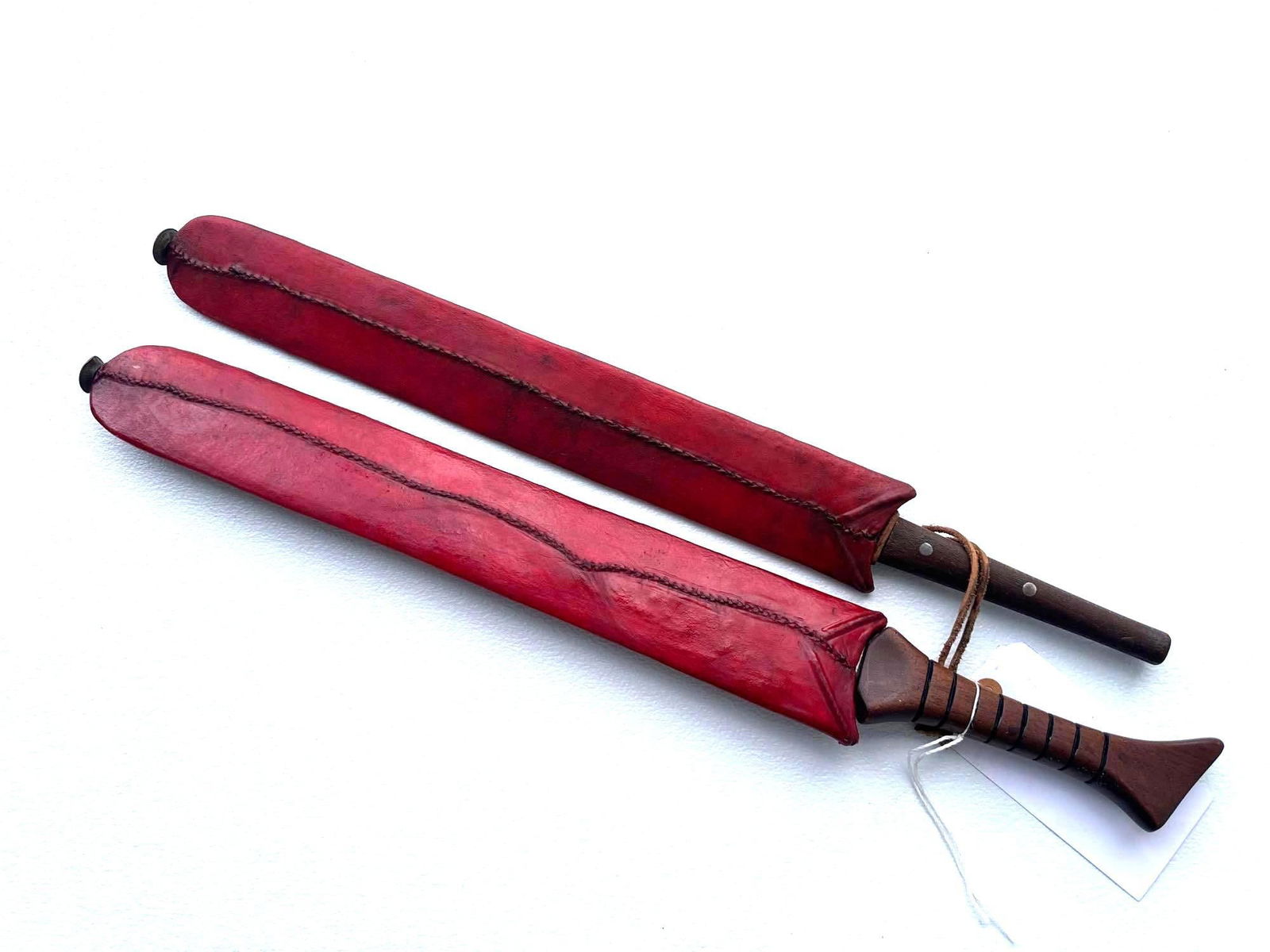 PAIR OF VINTAGE KENYAN MACHETES: 22.5" LONG A pair of vintage Kenyan machetes likely represents traditional tools that are deeply rooted in Kenyan culture and history. Machetes in Kenya have been essential tools for agricultural