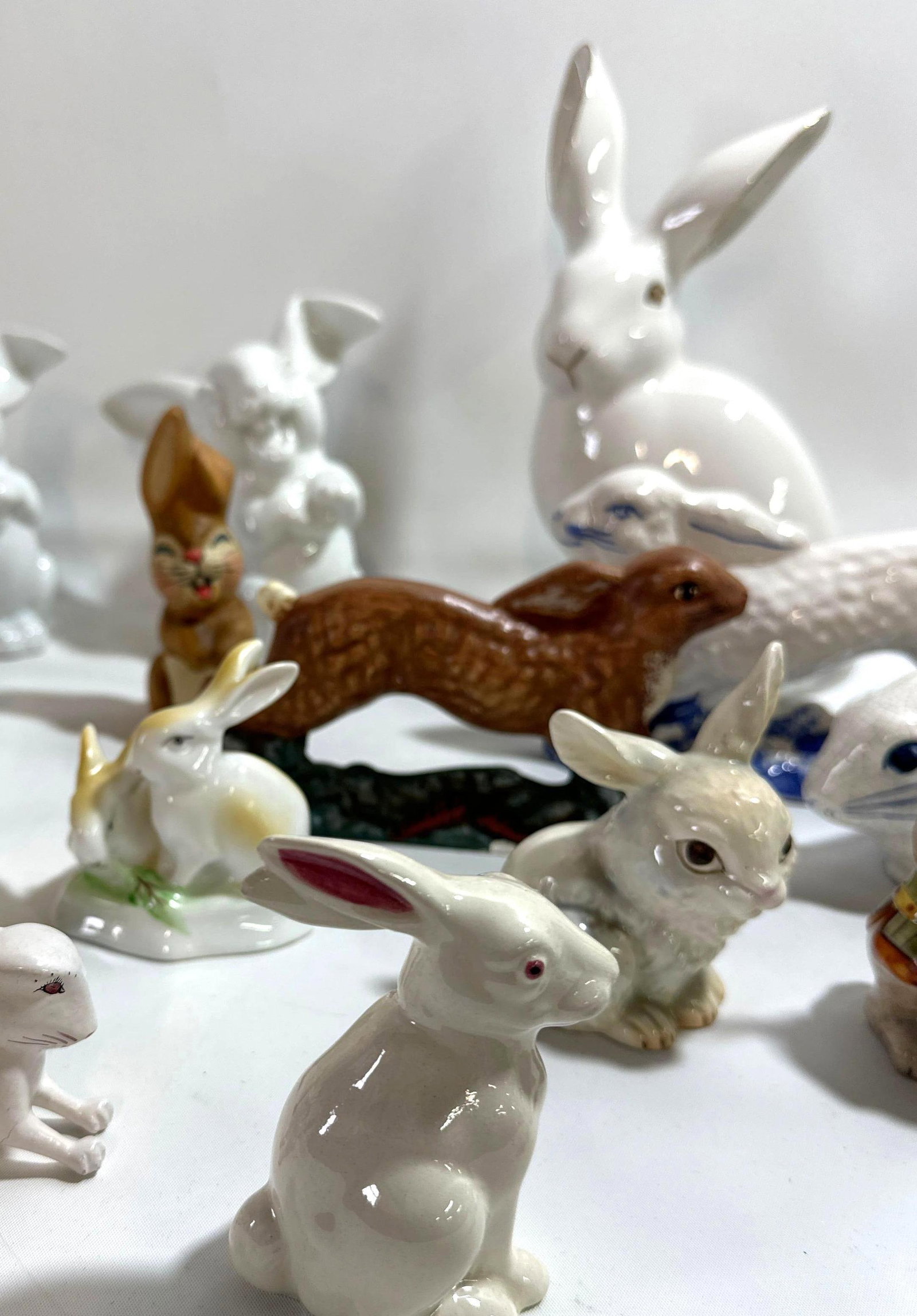 A FLUFFLE OF BUNNY RABBIT STATUES: This delightful menagerie of porcelain, ceramic, and papier-mâché rabbits presents a charming collection of varying finishes, colors, and makers, perfect for collectors of whimsical animal figurines