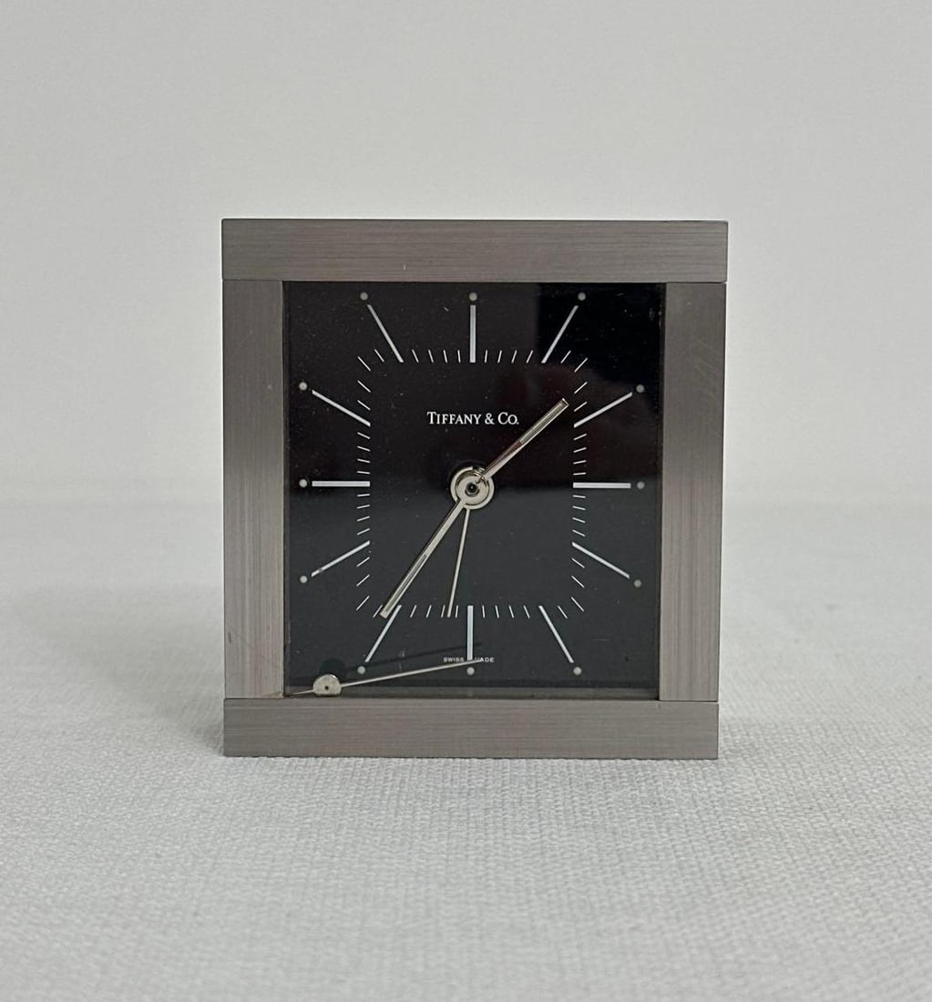 TIFFANY & CO. RHODIUM ALARM CLOCK: This sleek and elegant Tiffany & Co. rhodium alarm clock is a testament to the brand's renowned design aesthetic. The clock features a minimalist design with a square face and a clean, modern 