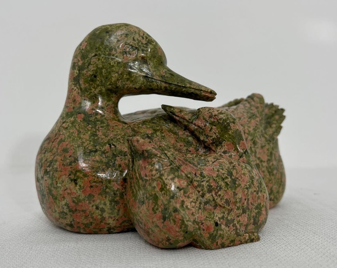 CARVED UNAKITE DUCK WITH DUCKLING STATUE: This charming Unakite sculpture depicts a mother duck tenderly sheltering her duckling. Unakite, a unique combination of pink orthoclase and green epidote, lends a warm, earthy tone to the piece. The 