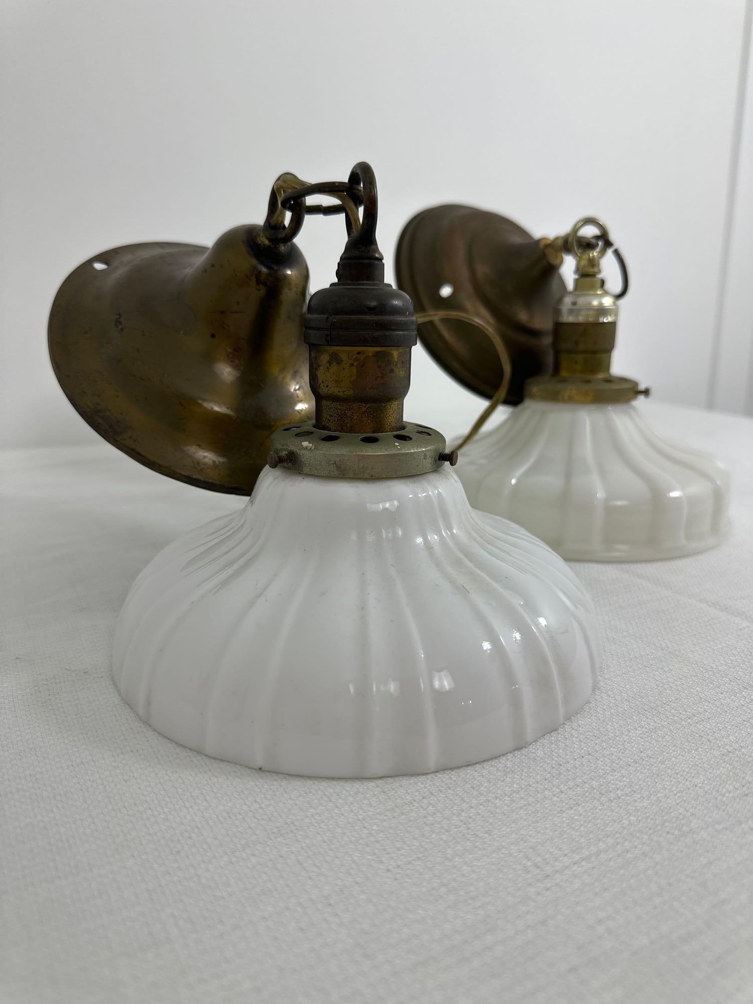 NEAR PAIR OF MILK GLASS PENDANT LIGHTS: This charming pair of near-identical milk glass pendant lights offers a touch of vintage elegance to any space. Each light features a delicate white milk glass shade with a fluted design, creating a s