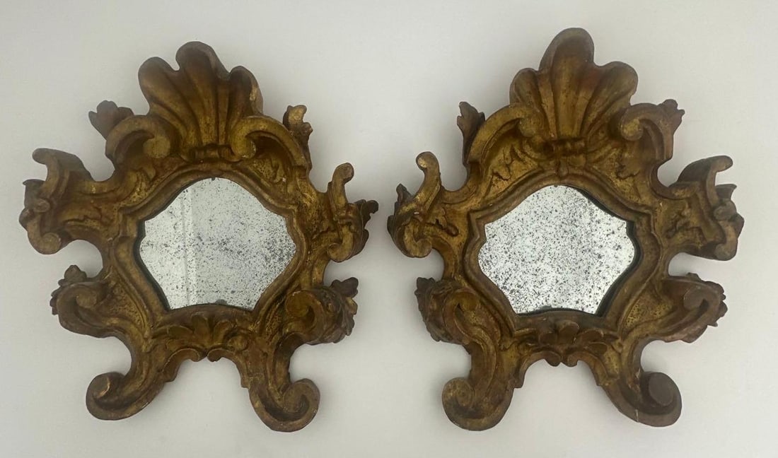 PAIR OF ANTIQUE CHALKWARE GOLD LEAF PLASTER MIRRORS: This elegant pair of antique mirrors showcases the opulence and artistry of the Florentine/ Rococo style. Crafted from chalkware and adorned with rich gold leaf, the frames feature intricate carvings