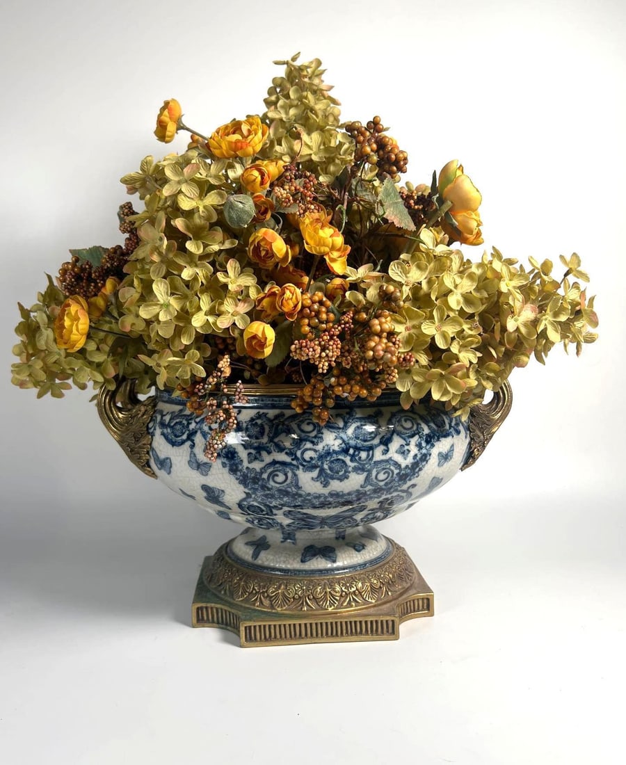 CHINESE UNITED WILSON JUMC PORCELAIN PLANTER JARDINIERE W/ FLORAL ARRANGEMENT: A display of elegance, this Chinese United Wilson JUMC porcelain planter jardiniere features a classic blue and white design, complemented by a meticulously arranged faux floral arrangement, standing 