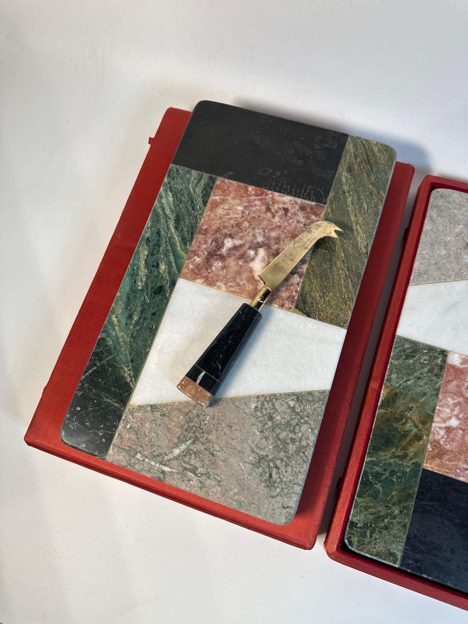 VALUE LOT: PAIR OF MARBLE CHEESE BOARDS WITH KNIVES: This pair of marble cheese boards, each measuring 13"x7", offers a luxurious serving experience for cheese enthusiasts and entertainers alike. Crafted from a beautiful assortment of natural ma