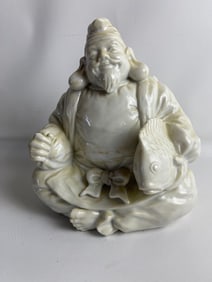 WHITE PORCELAIN SEATED FIGURE OF ASIAN MALE EBISU WITH FISH