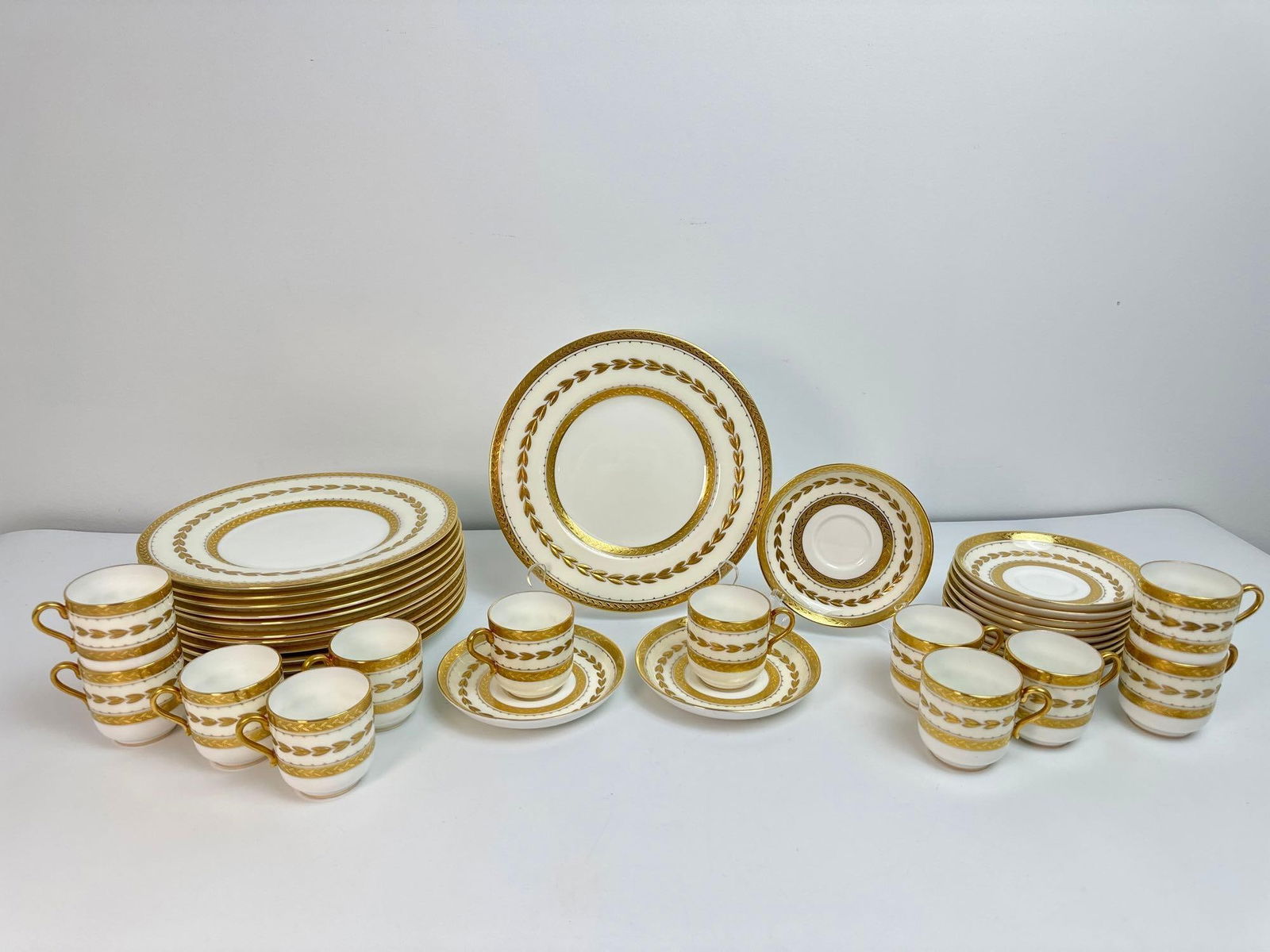 MINTON FOR TIFFANY & CO. 36 PIECE BONE CHINA SET: A bone china set PATTERN H-4923 22K GOLD LAUREL, GOLD ENCRUSTED BORDER COLLECTION INCLUDES: 12 DINNER PLATES 9IN DIAMETER *ONE WITH CHIP, PICTURED 12 SAUCERS 5IN DIAMETER 12 TEA/ESPRESSO CUPS 2.25IN