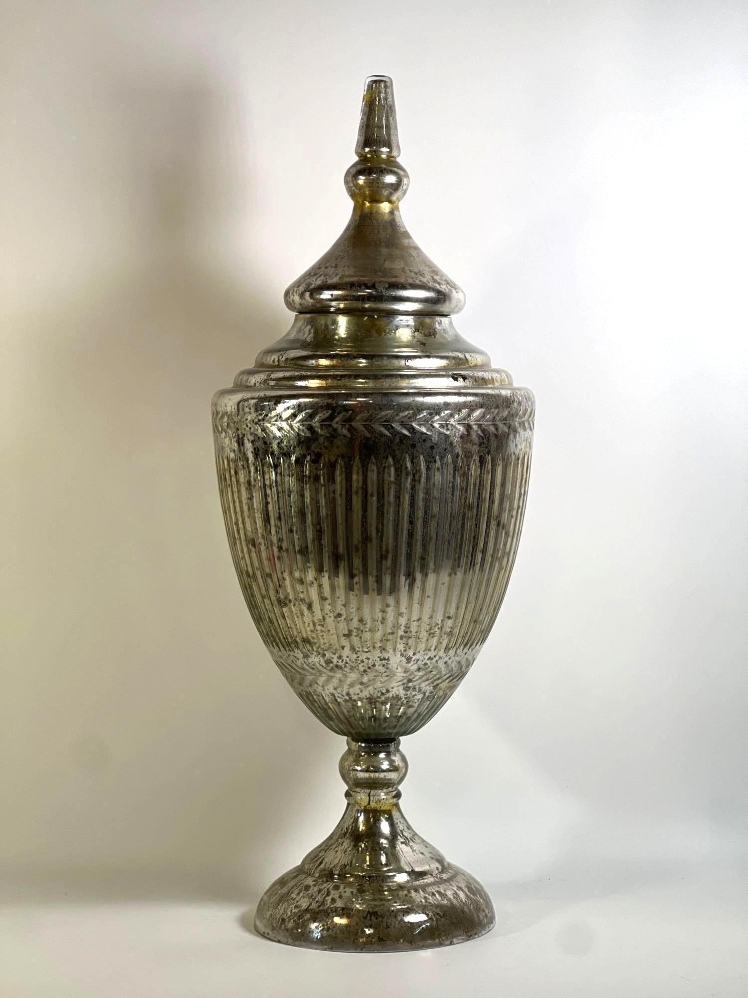 LARGE VINTAGE MERCURY GLASS APOTHECARY JAR: A large vintage mercury glass apothecary jar with a removable, multi-tiered lid and a footed base, displaying a distressed, reflective silver finish. Dimensions: 28"H Artist or Maker: Unknown, lik