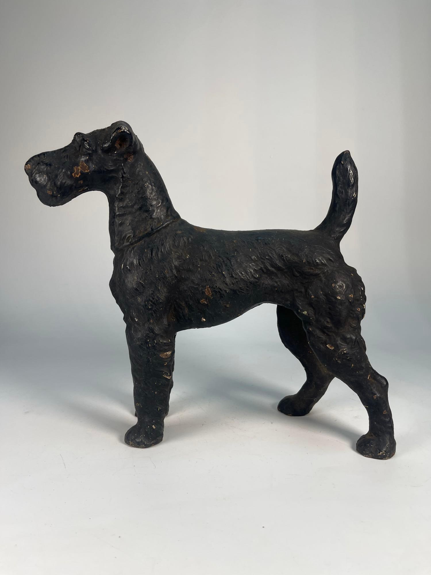 CAST IRON DOG STATUE / DOORSTOP: A cast iron statue or doorstop depicts a standing dog with a wiry coat, a long muzzle, and a docked tail. Based on its features, it appears to be a Terrier. Dimensions: 10.50" X 10.25" Artist 