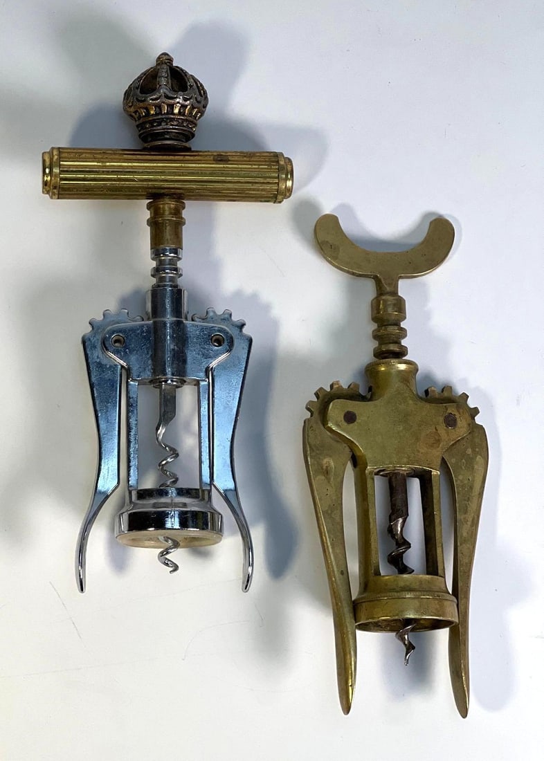 PAIR OF VINTAGE WING CORKSCREWS: ONE WITH CROWN DETAIL: A pair of vintage wing corkscrews, one constructed of brass and stainless steel with a decorative crown detail on the handle, and the other made of heavy brass with a more ornate, openwork design. Dim