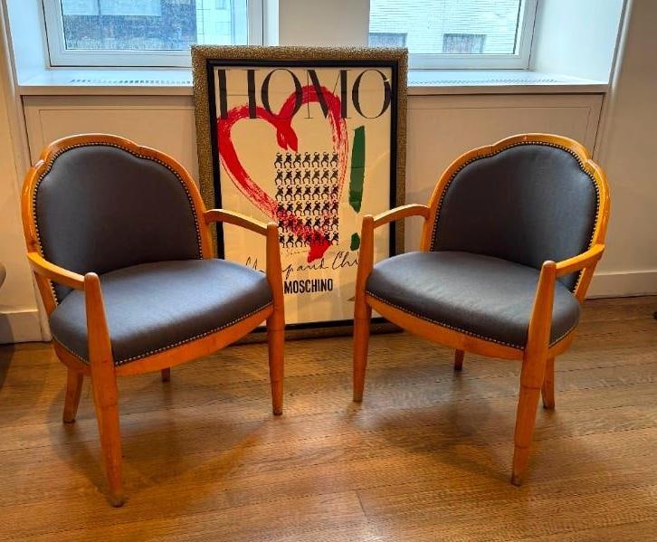 PAIR OF 1930's ART DECO UPHOLSTERED ARMCHAIRS WITH NAILHEAD DETAIL: A pair of Art Deco armchairs, each featuring a curved back, wooden frames, dark upholstered seats and backs with nail head trim, and angled legs. From the Moschino NYC showroom. Dimensions: 24 x 20 x