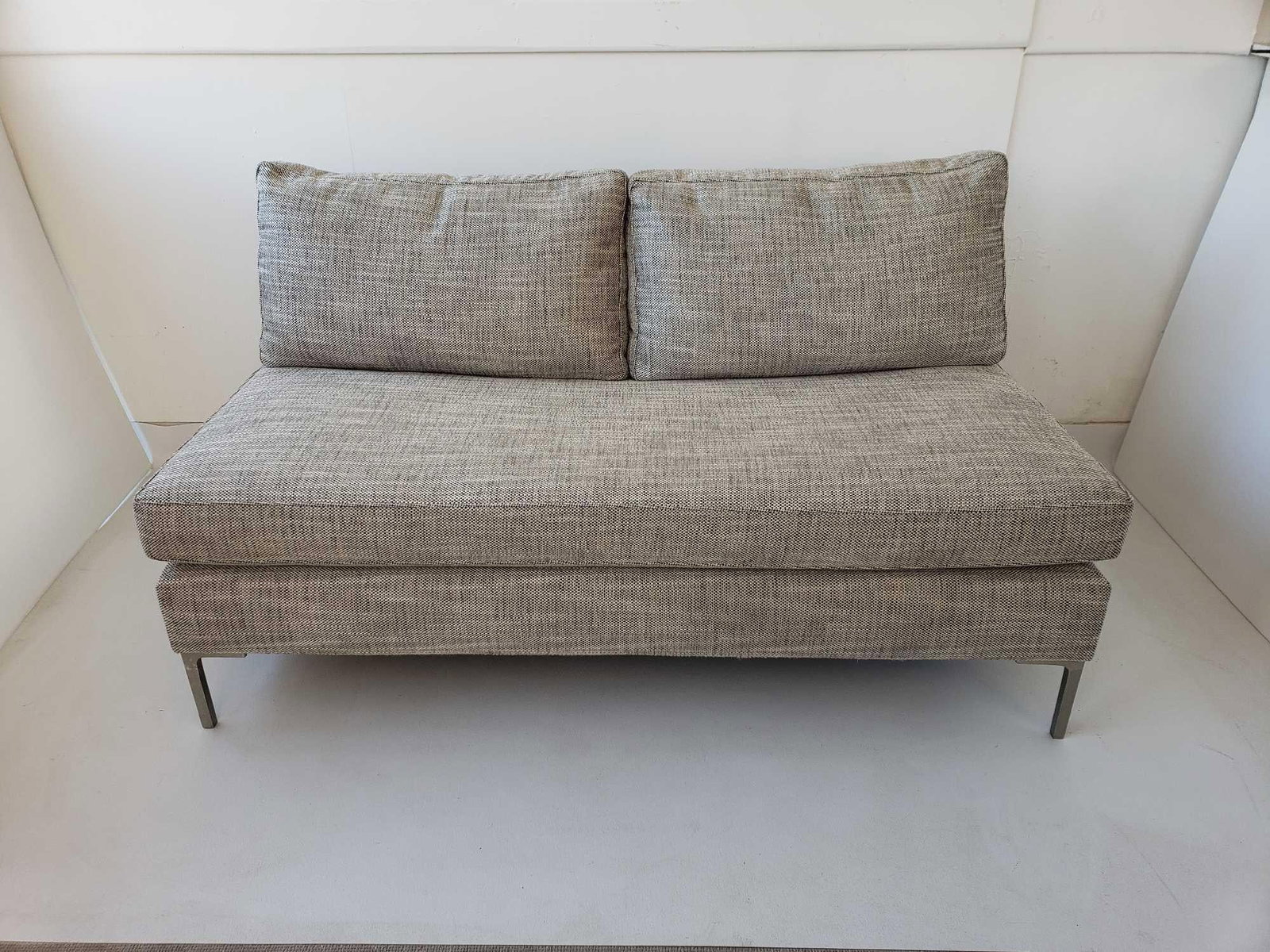 MCCREARY MODERN 0577 SERIES ARMLESS LOVE SEAT: This is an armless loveseat from the McCreary Modern 0577 series, featuring a low profile, two loose back cushions, and upholstered in a textured, light-colored fabric, supported by thin metal legs.