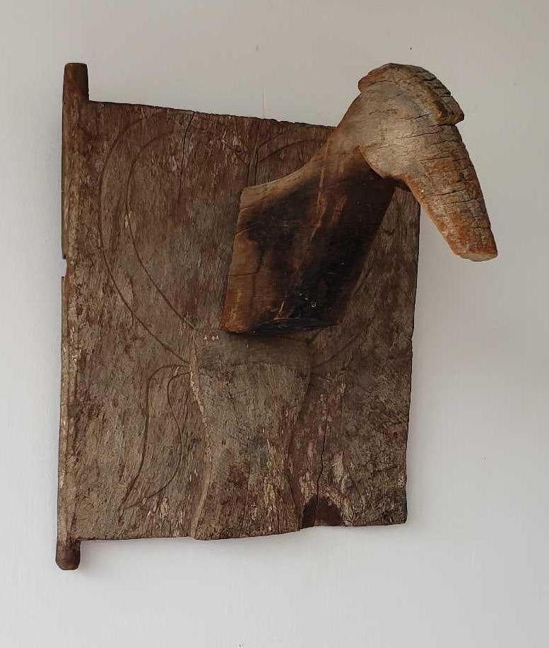 CARVED WOOD TORAJA GRANARY DOOR WITH ANIMAL HEAD: A carved wooden Toraja granary door from Borneo, featuring an animal head protruding from the center of the rectangular panel, with incised designs on the surrounding wood. Dimensions: 19.25"h x 16"w 