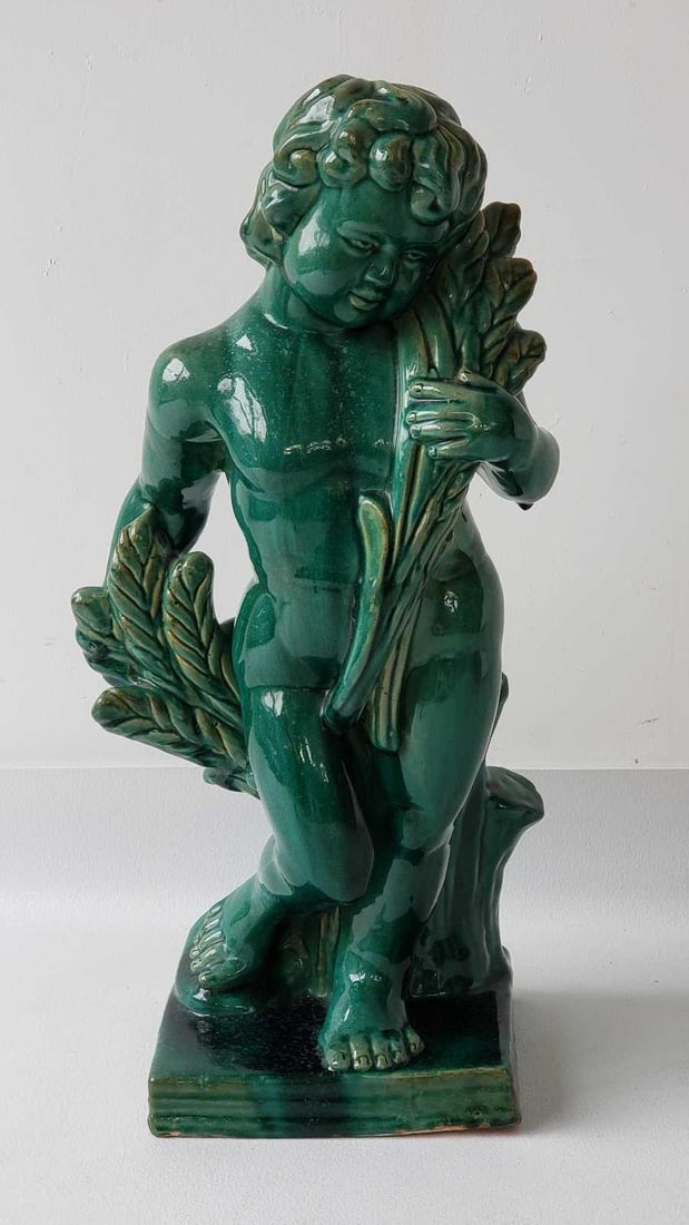 MAJOLICA STYLE GLAZED TERRACOTTA PUTTI STATUE: A Majolica style glazed terracotta statue of a putto, featuring a vibrant, colorful glaze. Dimensions: 26.5"h Artist or Maker: In the style of Majolica Notes: Although care is taken to photograph 