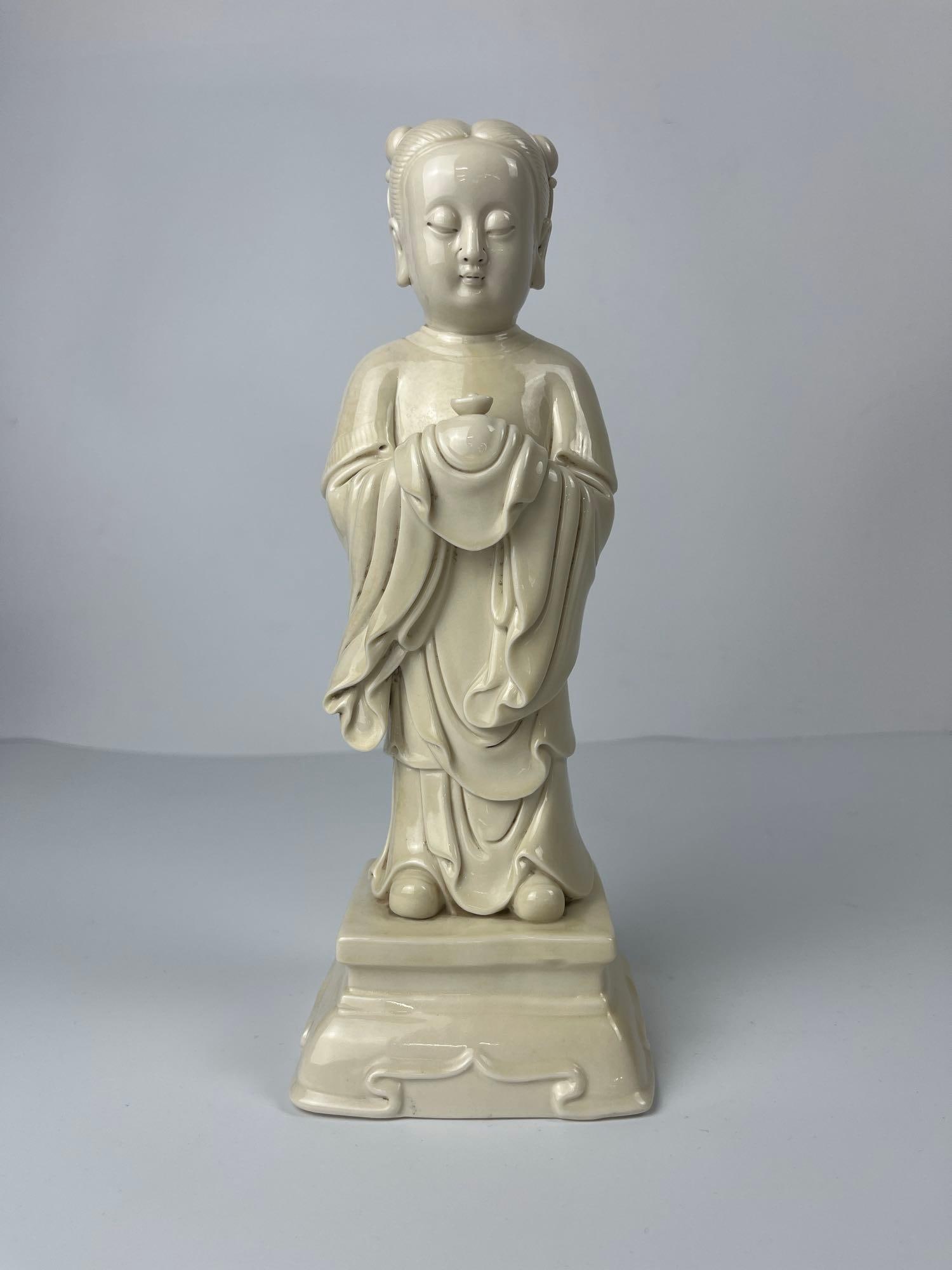 VALUE LOT: BLANC DE CHINE CHINESE PORCELAIN FIGURE OF GUANYIN HOLDING VASE: A "Blanc de Chine" Chinese porcelain figure depicting a seated deity, who appears to be Guanyin based on the serene expression and posture, holding a vase or similar vessel in both hands. Es