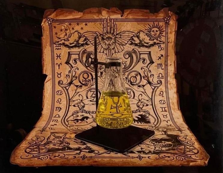 PHOTOGRAPH BY CHRISTINA STOW "OIL": A photograph by Christina Stow titled "Oil," showcasing a still life composition featuring a flask with yellow liquid against a backdrop of an intricately detailed scroll with symbolic motifs, all pre