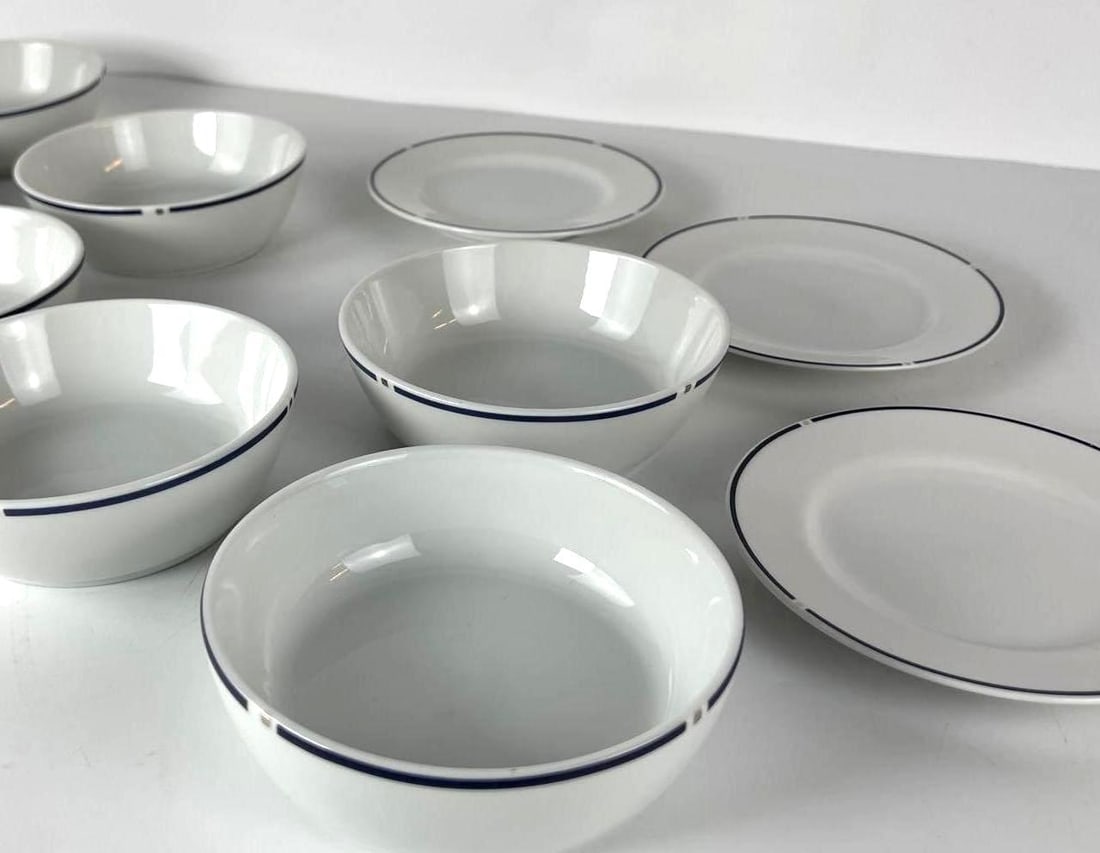 GWATHMEY SIEGEL FOR SWID POWELL AMERICAN AIRLINES DISHES: A collection of Gwathmey Siegel for Swid Powell American Airlines bowls and dishes, each piece crafted from white porcelain with a distinctive thin blue band around its rim. 7 Bowls and 3 Plates Dime