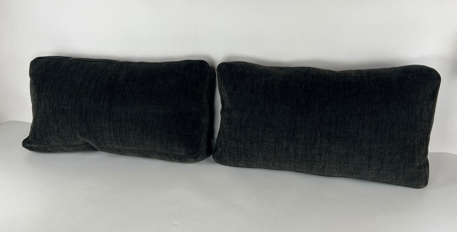 TWO EDRA PILLOWS: Two Edra pillows, each a rectangular cushion in a dark, textured fabric. Dimensions: 26” x 14” x 8” Artist or Maker: Edra Provenance: A New York Collector Notes: Although care i