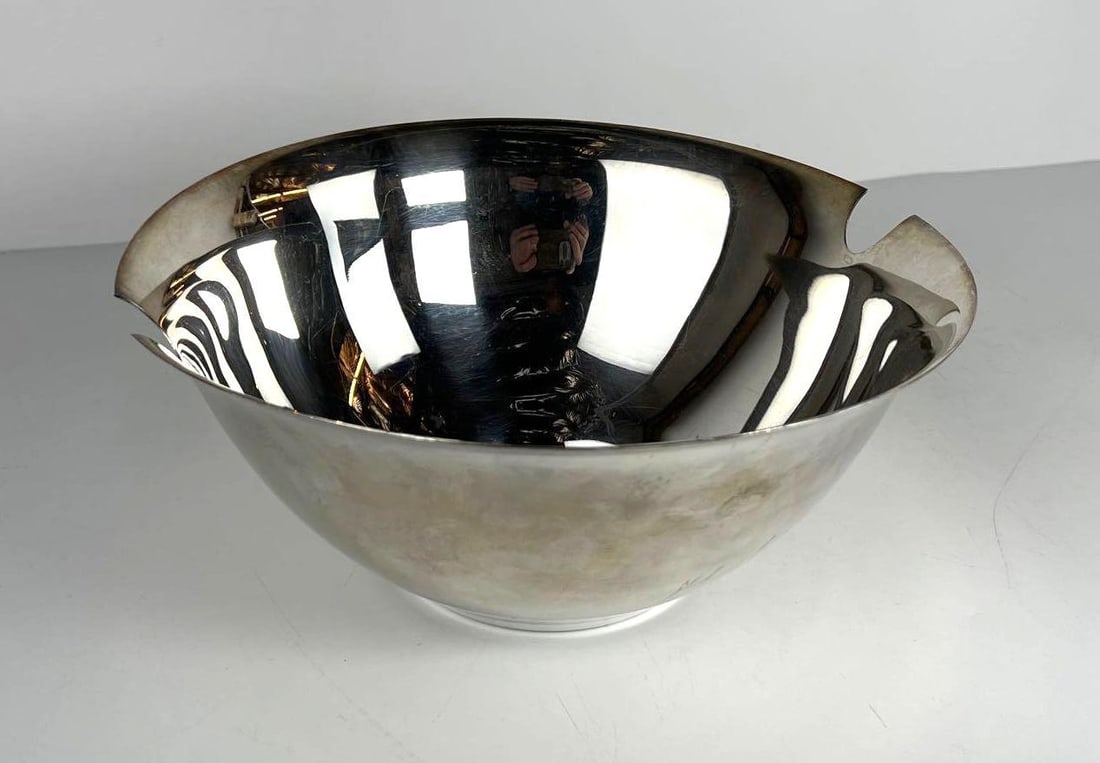 SWID POWELL TSAO and MCKOWAN SILVER PLATE SALAD BOWL: A Swid Powell silver plate salad bowl, featuring a polished, reflective interior and exterior, with an irregular rim. Dimensions: 11.25” D x 5” H Artist or Maker: Swid Powell / Tsao and
