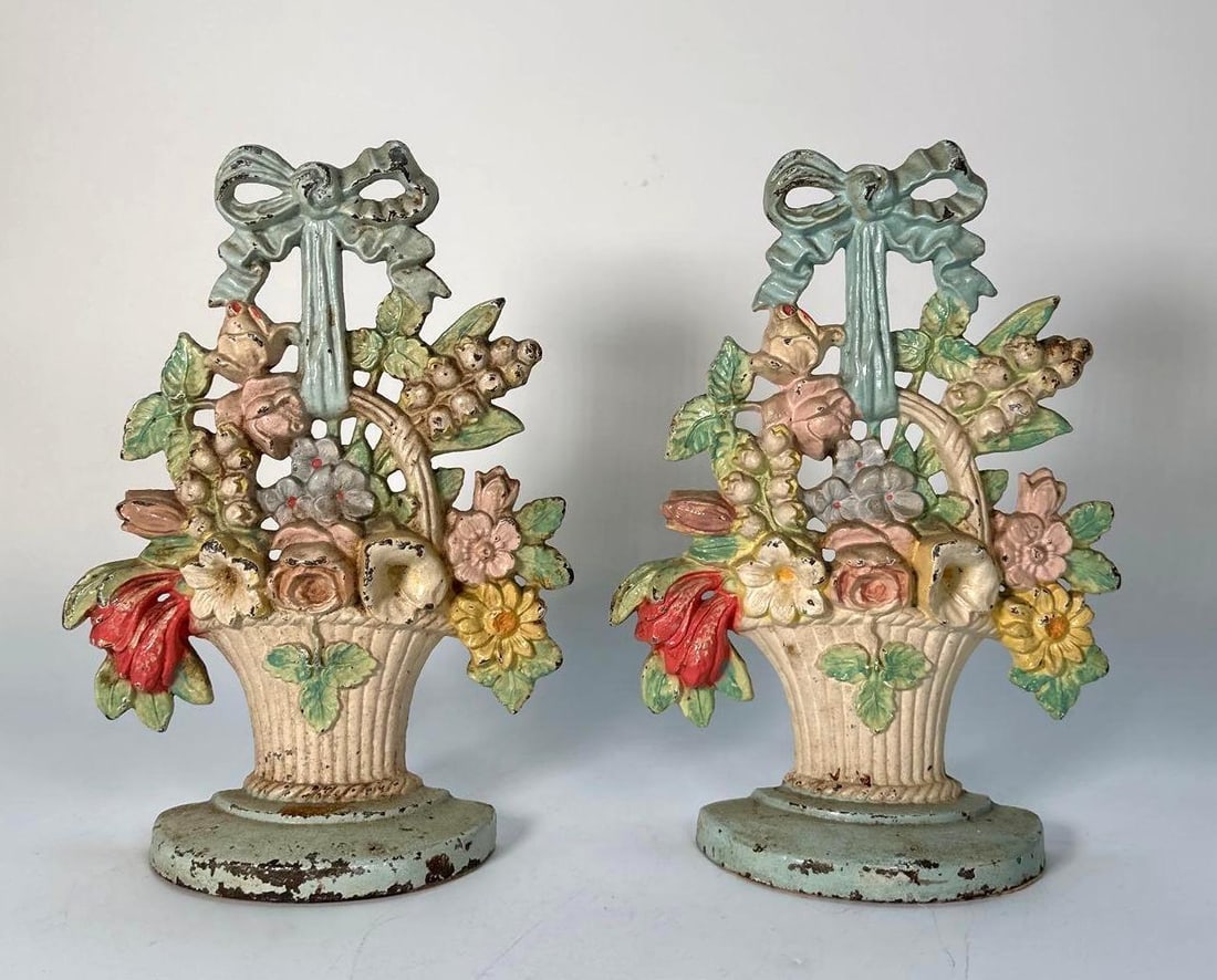 PAIR OF VINTAGE CAST IRON DOORSTOPS WITH ORNATE FLORAL BASKET MOTIF AND POLYCHROME FINISH: A pair of vintage cast iron doorstops, featuring an ornate floral basket motif and a polychrome finish. Dimensions: 10.5"T X 7.25"W Artist or Maker: Unknown Provenance: A Prominent New York Retail