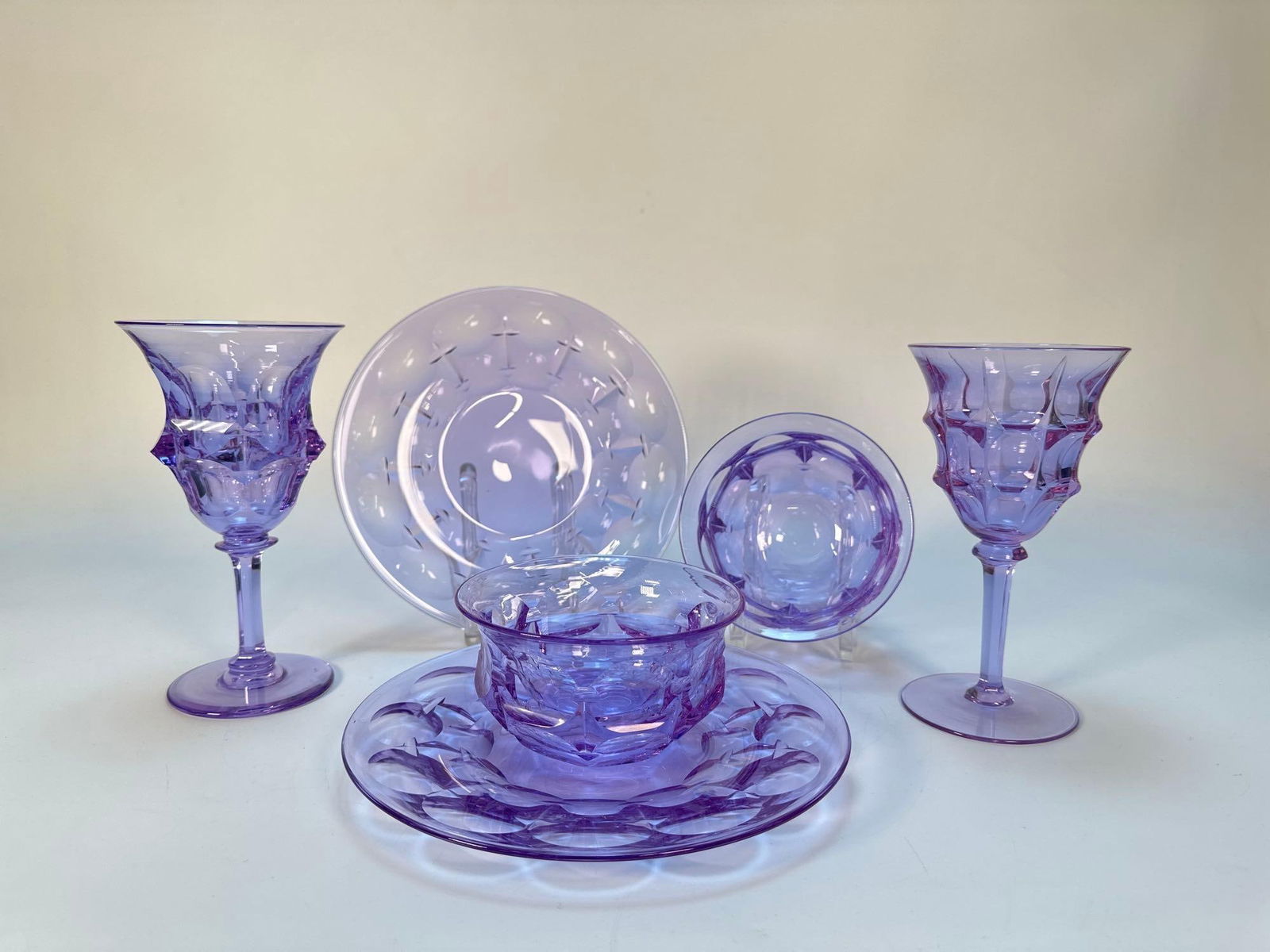 RARE 30 PIECE MOSER ATTR. AND STEUBEN PURPLE TO BLUE ALEXANDRITE / NEODYMIUM GLASS MIXED DINNER SET: This is a collection of various Alexandrite / Neodymium glass tableware pieces, including plates, bowls, and stemmed goblets, exhibiting decorative faceted and textured patterns Finer-pieces in a simi