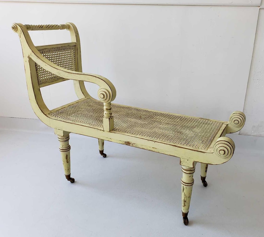 PAINT DECORATED CANED RECAMIER: A yellow painted recamier with a caned seat and backrest, an scrolled armrest, and turned legs, all in a light, distressed finish. Dimensions: 34.75"H x 42.75"L x 17.25"D Artist or Maker