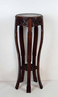 CHINESE CARVED HARDWOOD PEDESTAL / PLANT STAND: A Chinese carved pedestal/plant stand. The stand is crafted from a dark, rich wood and features a round top, supported by a central column and four carved, splayed legs that connect to a lower, ornate