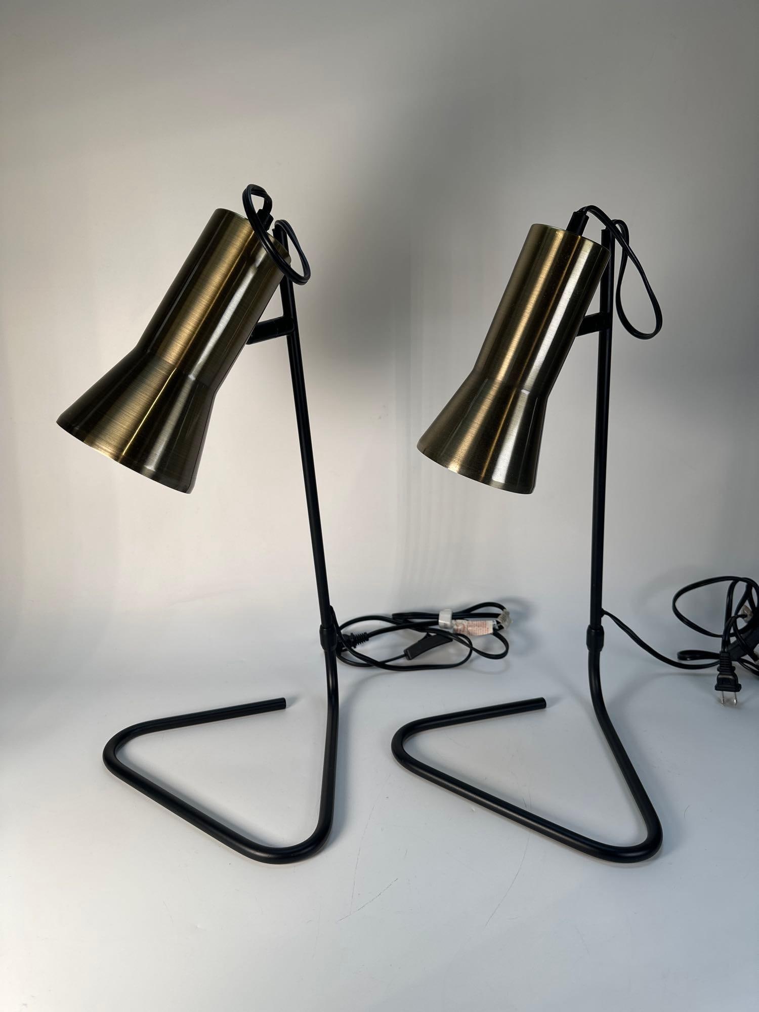 PAIR OF MID-CENTURY MODERN LAMPS: A pair of mid-century modern lamps, each featuring a brushed brass-toned cylindrical shade atop a black metal, triangular-shaped base. Dimensions: 19.5"T x 10.25"W Artist or Maker: Unknown Pro