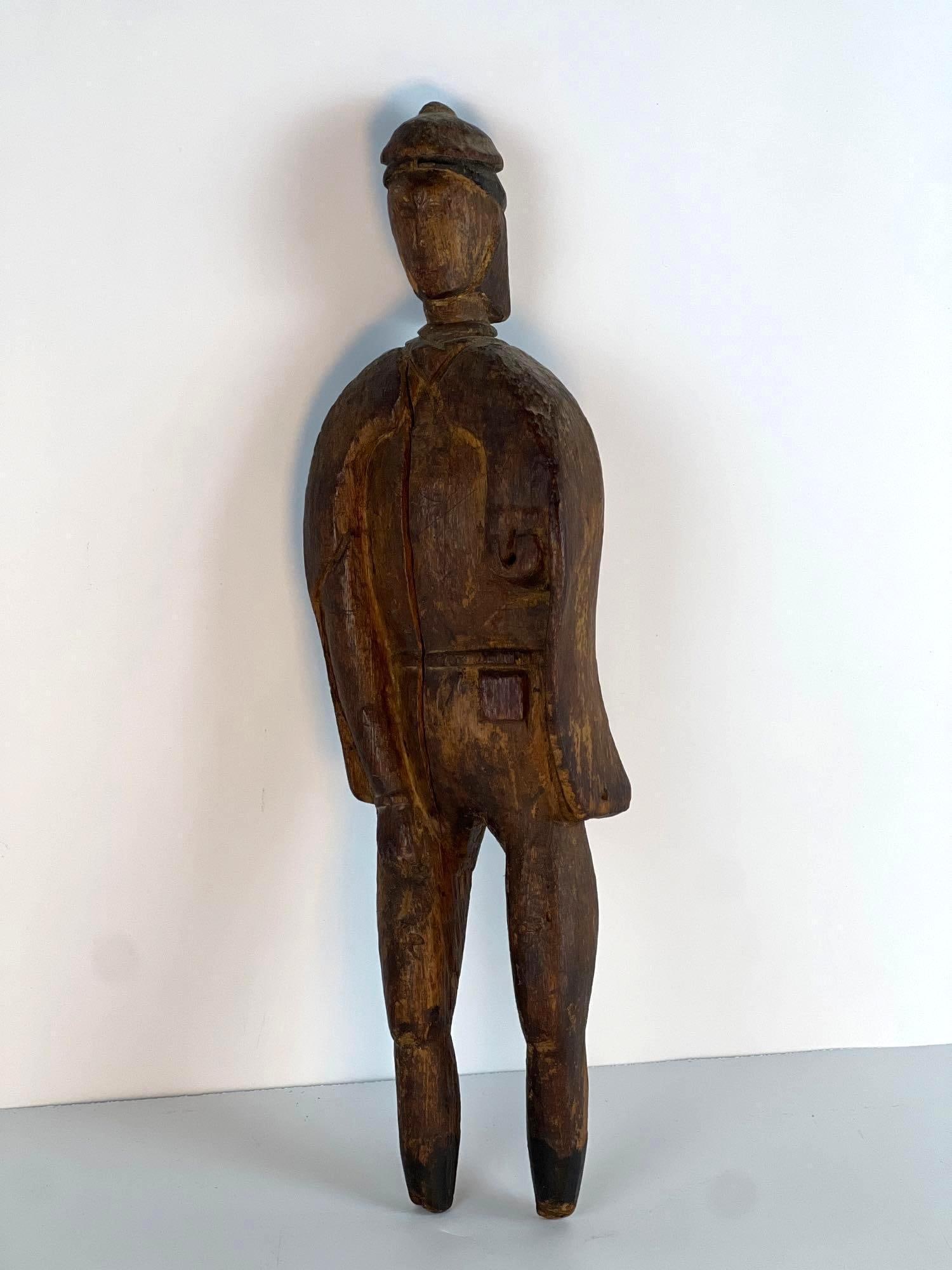 VALUE LOT: ANTIQUE WOODEN FIGURINE OF MAN: *An antique carved wooden figurine of a standing man, with a dark, distressed finish, simplified features, and a somewhat elongated form. Dimensions: 17.5" x 5" x 2" Artist or Maker: Unkno