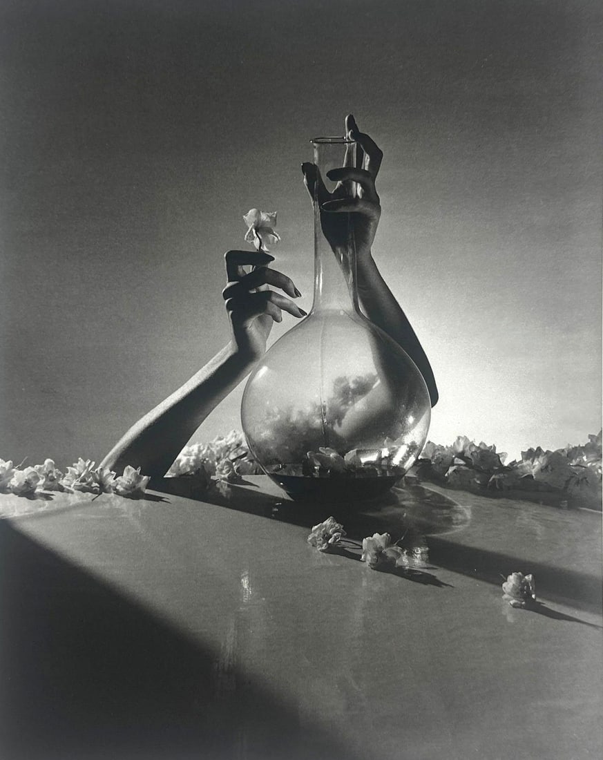 HORST, SURREAL FLOWER ARRANGEMENT 1941, SHEET-FED GRAVURE, 1992 JAPAN: *A black and white photo print depicting a surreal arrangement with hands holding a tall, bulbous glass vase and a small white flower, surrounded by scattered white flowers. (with certificate of authe