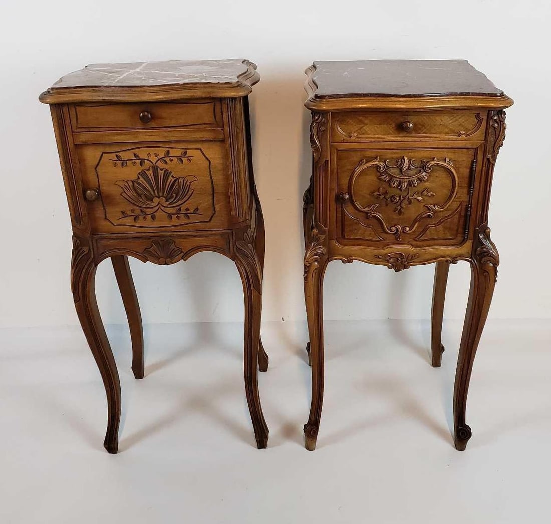 TWO ROUGE MARBLE TOP CARVED WALNUT LOUIS XV PETITE COMODES: *A pair of Louis XV style petite commodes, or nightstands, crafted from carved walnut and topped with rouge marble. They feature ornate details on the drawers and cabinet doors, and rest on curved cab
