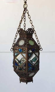 BRONZE MOROCCAN STYLE HANGING FIXTURE WITH BEVELED AND COLORED CAMEO GLASS INSETS: Antique Brass and Stained Beveled Glass Hanging Lantern Pendant Light Dimensions: 19"h x 10.5"w x 10"d Artist or Maker: Unknown Provenance: A New York Collector Notes: Although care