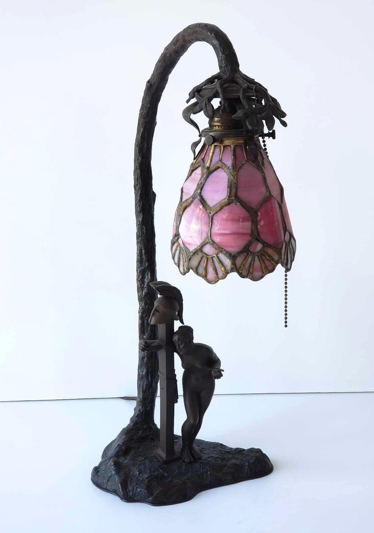 BRONZE ART NOUVEAU CLASSICAL MOTIF FIGURAL TABLE LAMP WTH TIFFANY STYLE SHADE: Antique Art Nouveau Bronze Figural Table Lamp with Pink Slag Glass Shade depicting nude female maiden and Roman Soldier herm on base. Dimensions: 20.25"h Artist or Maker: Unknown Notes: Althoug
